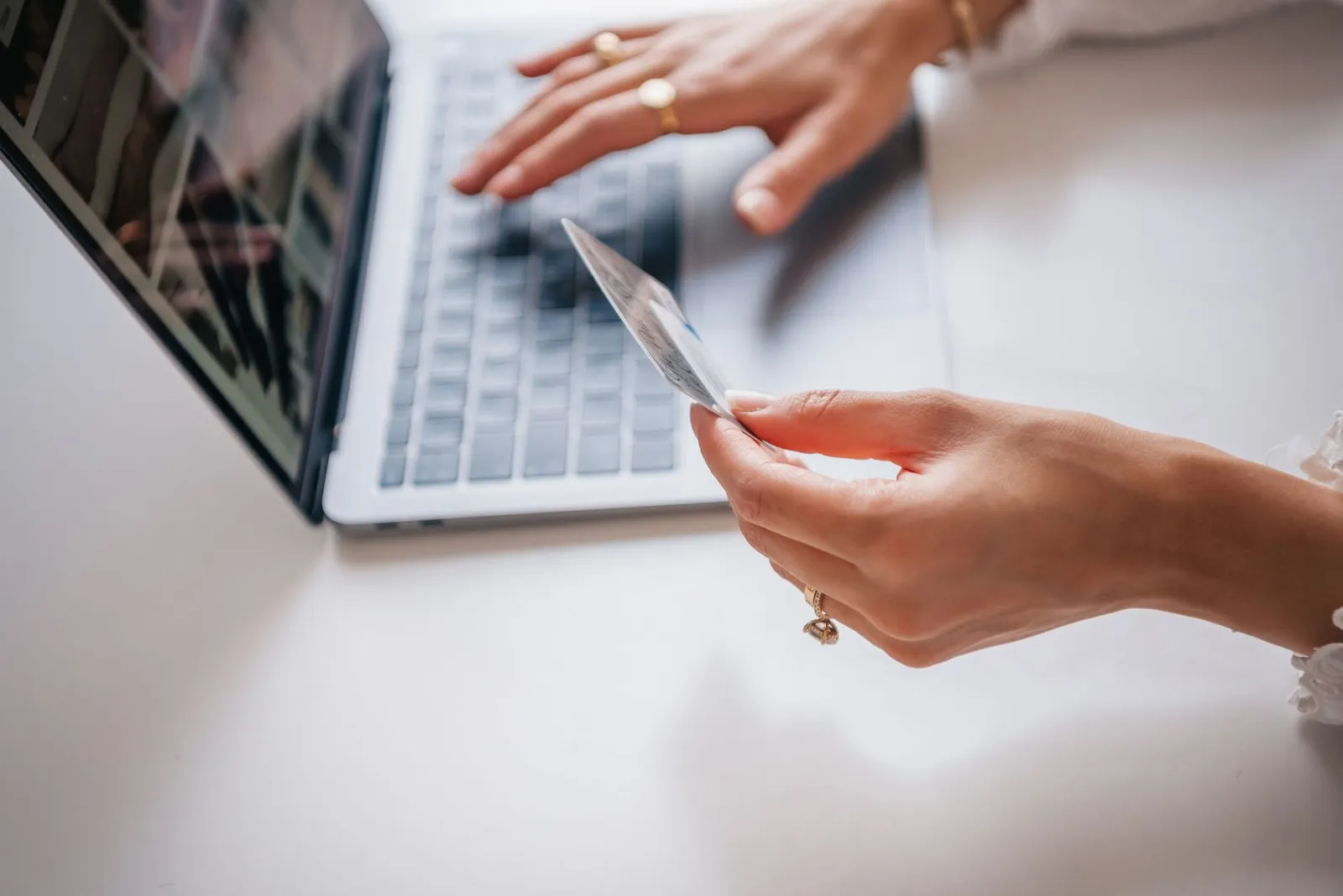 A woman holding a credit card while working at a laptop