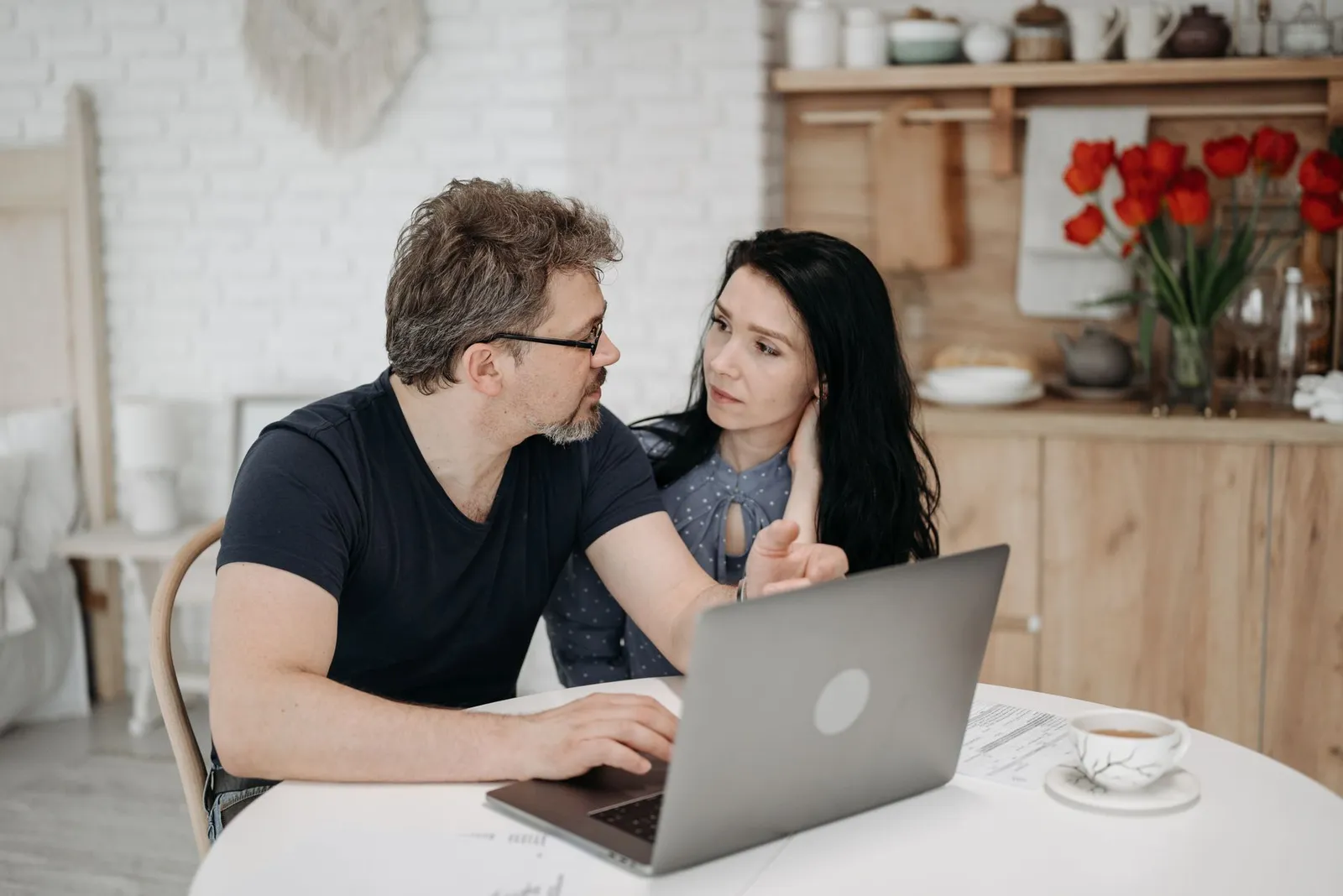 A couple reviewing questions together on a laptop at their kitchen table