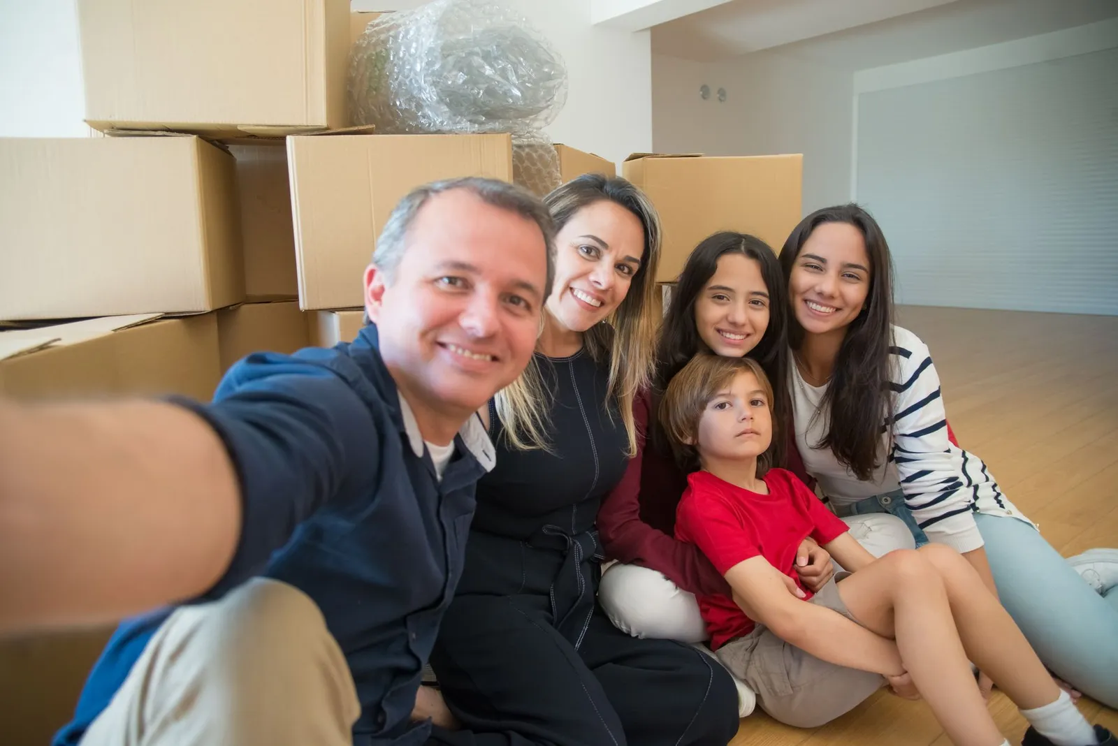 A family taking a selfie surrounded by moving boxes in their new home