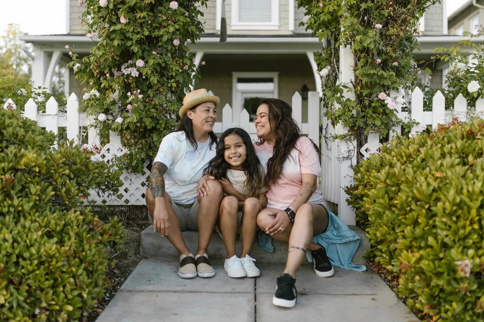 A family of three sitting together outside their home