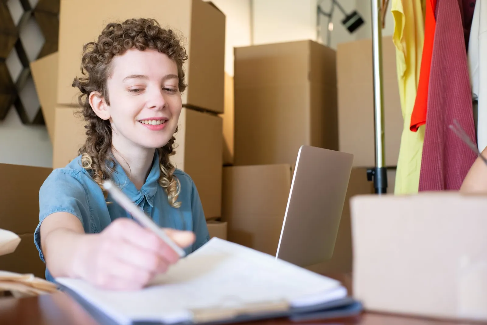 A small business owner working with a laptop among packed orders